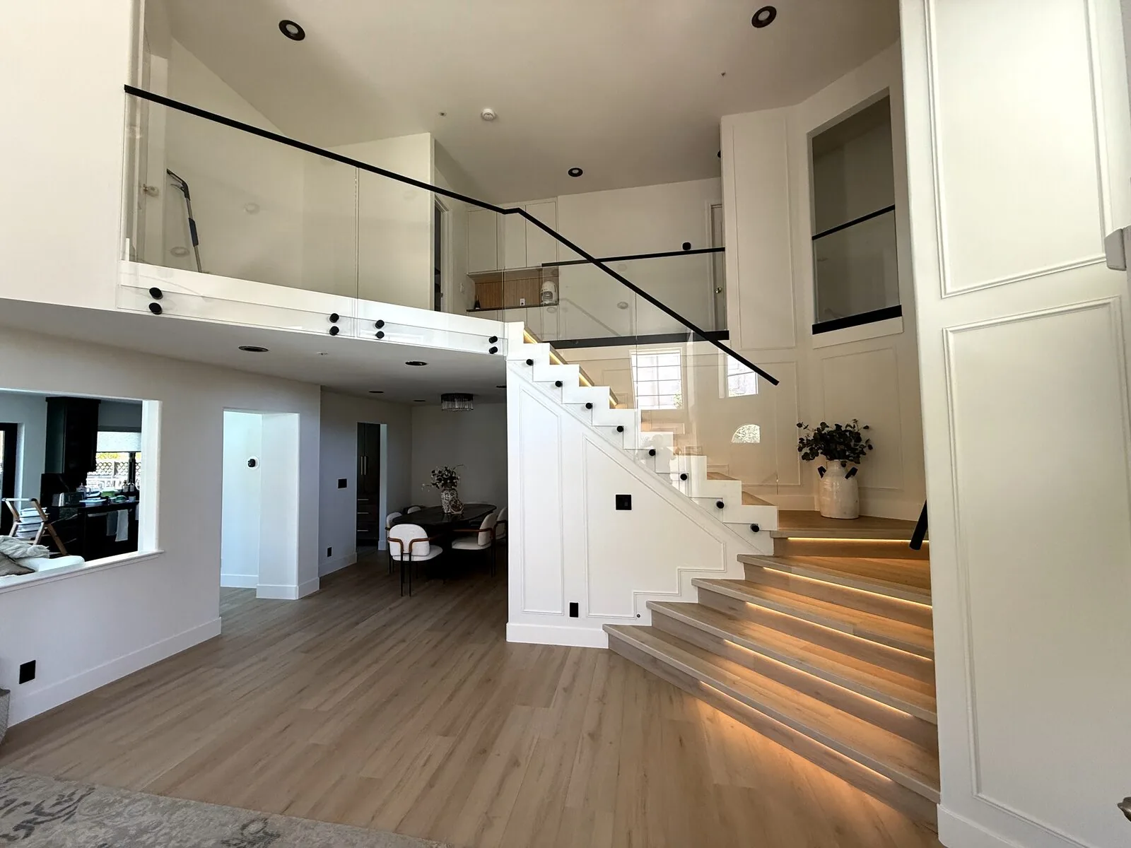 Frameless glass railing along a two-story loft overlooking the lighted staircase and living area of a Folsom home