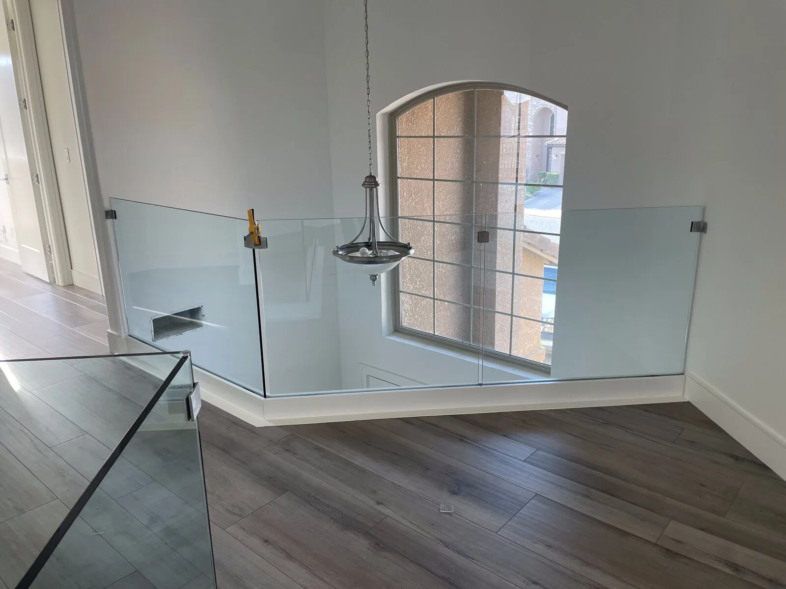 Glass railing panels following the landing corner beside the arched window