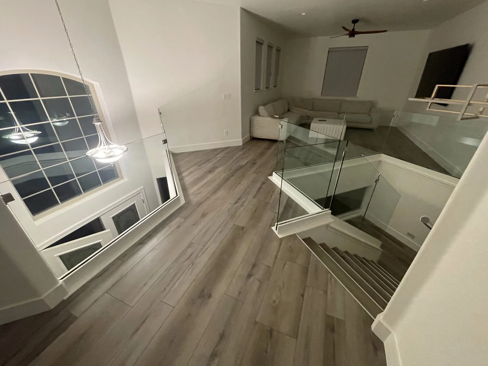 Evening view of the glass-wrapped stair opening from the upstairs loft