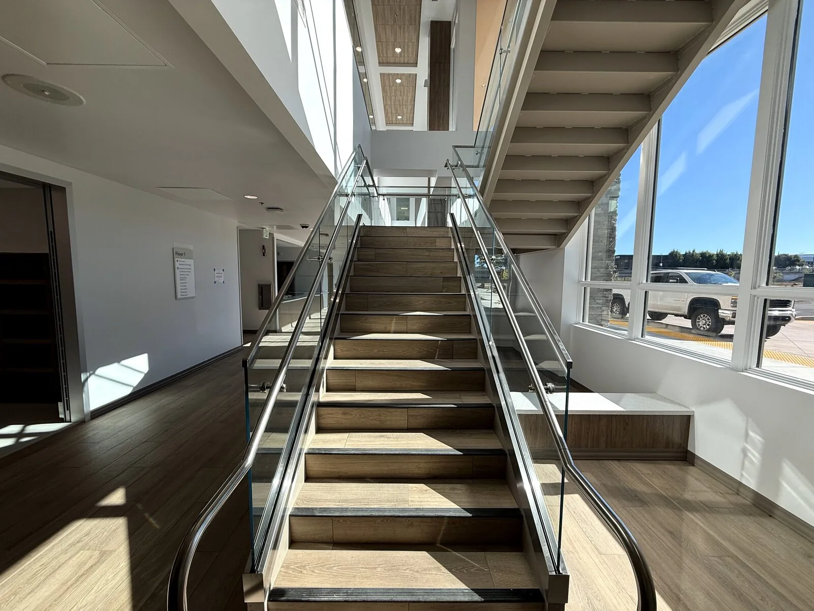 Straight-on view of the commercial staircase with glass guards and stainless handrails on both sides