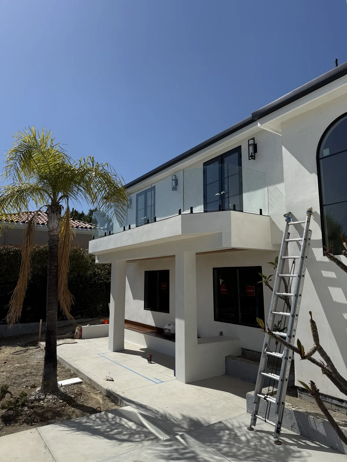 Frameless glass balcony railing on the modern white two-story home above the deck