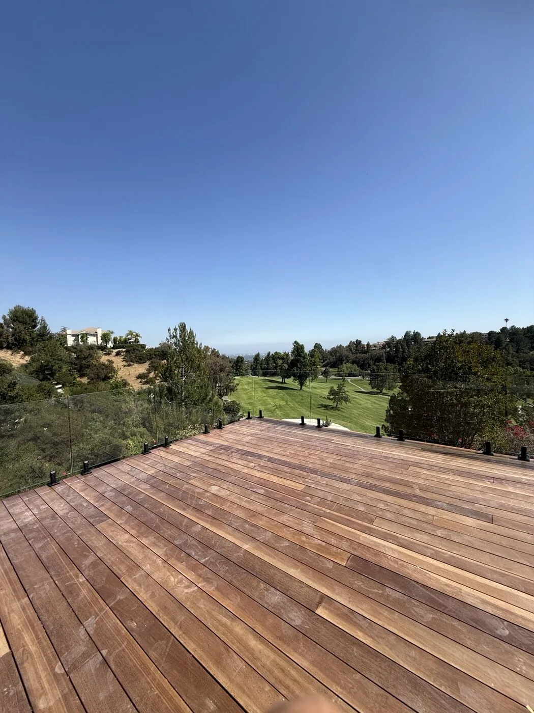 Frameless glass deck railing we installed along the edge of a hillside wood deck overlooking a California golf course